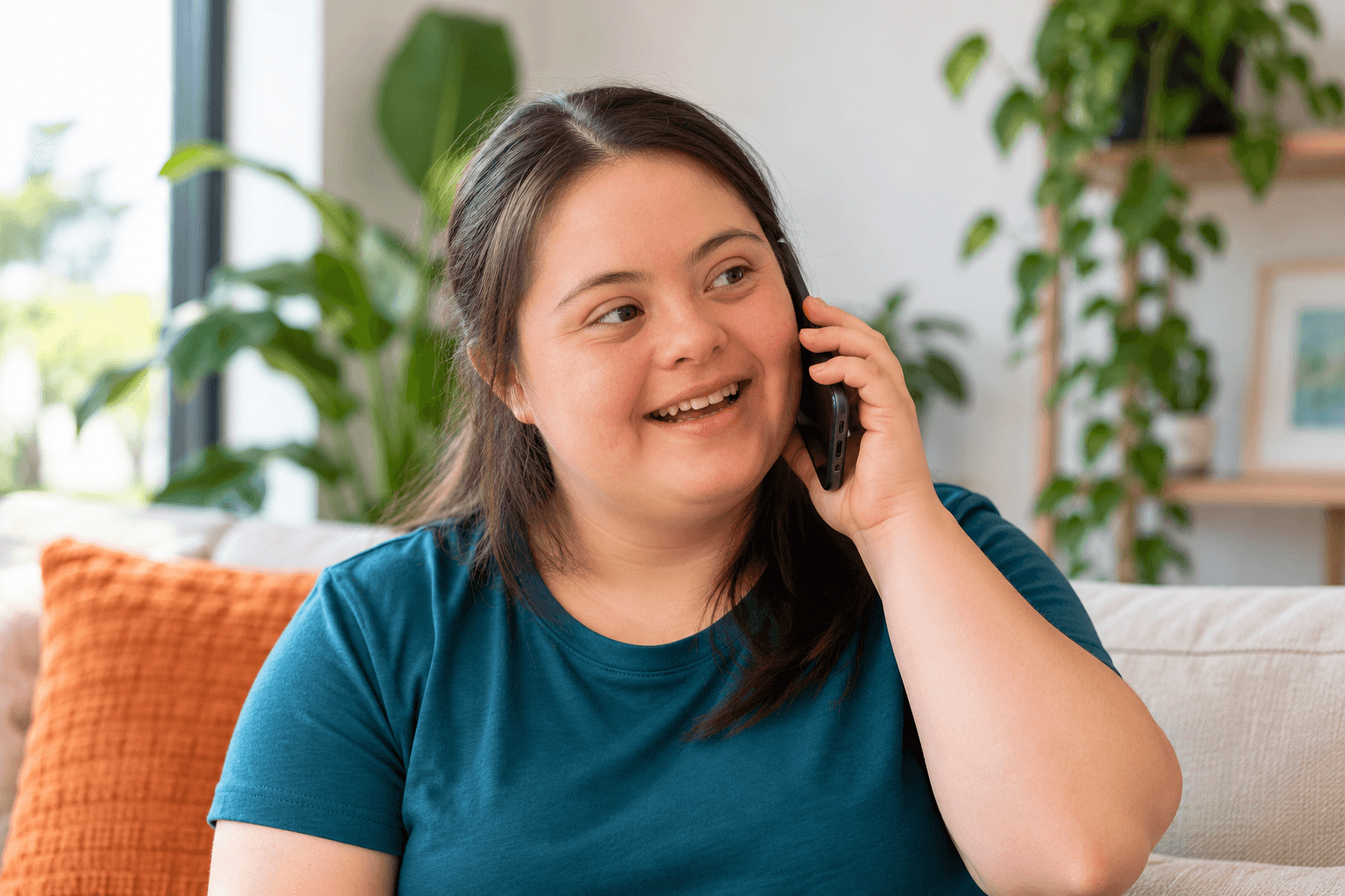 A smiling woman talking on the phone at home
